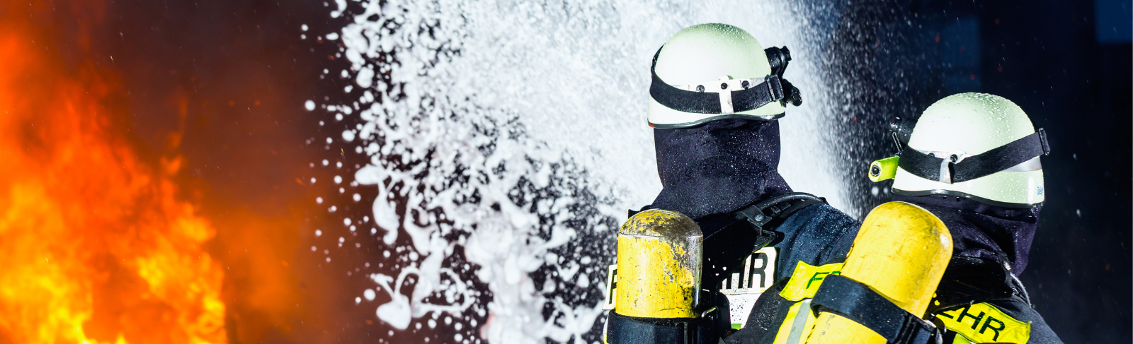 Firefighters spraying a foamy substance against big flames