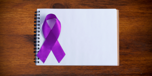 Overdose cause ribbon resting on a blank notepad, placed on wood surface.